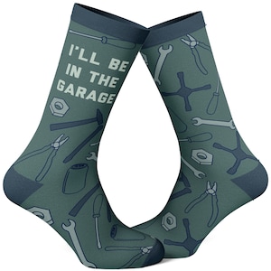 May include: A pair of green socks with a blue trim. The socks feature a variety of tools and the text "I'll be in the garage".