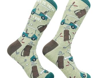May include: A pair of light green crew socks featuring a repeating pattern of golf carts, golf bags, and golf clubs. The text "THIS IS HOW I ROLL" is printed on the upper portion of the socks. The socks have dark brown heels and teal cuffs.
