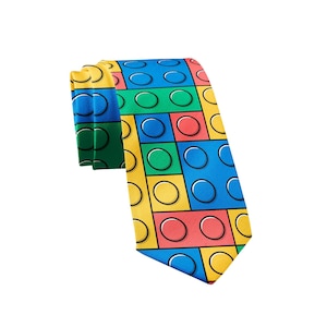 Puede incluir: Una corbata con un patrón repetitivo de bloques de construcción entrelazados en colores primarios que incluyen rojo, azul, amarillo y verde. El diseño imita la apariencia de ladrillos de plástico con pernos circulares en relieve en cada bloque.