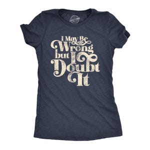 May include: Navy blue t-shirt with the text "I May Be Wrong but I Doubt It" in a vintage, distressed font. The shirt has short sleeves and a crew neck. The Crazy Dog brand logo is visible at the top.