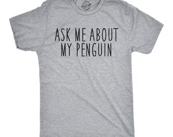 Op de afbeelding: Een grijs gemêleerd T-shirt met korte mouwen en de zwarte tekst "ASK ME ABOUT MY PENGUIN" op de borst. Het shirt heeft een ronde hals en een standaard pasvorm, met een klein rond logo zichtbaar aan de binnenkant van de kraag.