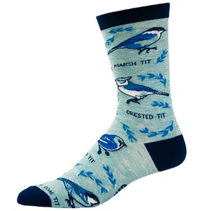 May include: A pair of blue and white socks with a light blue background. The socks feature a pattern of birds with the names "Marsh Tit", "Crested Tit", and "Coal Tit" written below each bird.