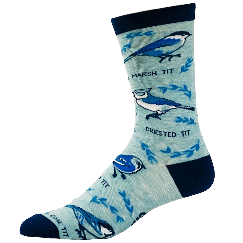 May include: A pair of blue and white socks with a light blue background. The socks feature a pattern of birds with the names "Marsh Tit", "Crested Tit", and "Coal Tit" written below each bird.