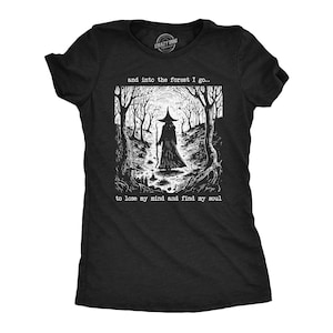 May include: A black short-sleeved t-shirt featuring a white graphic print of a figure in a pointed hat walking through a forest. The text above the graphic reads, "and into the forest I go..." and below the graphic reads, "to lose my mind and find my soul."