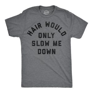Peut inclure: T-shirt gris chiné avec l'inscription noire "HAIR WOULD ONLY SLOW ME DOWN". Le texte est disposé en arc de cercle. Le t-shirt a un col rond et des manches courtes. Le logo Crazy Dog est visible sur l'encolure.