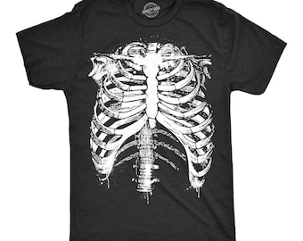 Puede incluir: Una camiseta negra de manga corta con un gran estampado gráfico blanco y detallado de una caja torácica humana en la parte delantera. El diseño incluye un esternón estilizado y costillas con un efecto de salpicaduras de tinta. Cuello redondo.