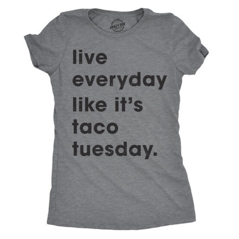 May include: A grey t-shirt with the slogan "live everyday like it's taco tuesday" printed in black. The top has a crew neck and short sleeves. A small circular logo is visible on the upper chest.