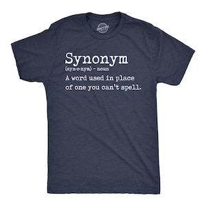 Può includere: T-shirt blu navy con la parola "Sinonimo" in bianco e la sua definizione: "Una parola usata al posto di una che non riesci a scrivere." La maglietta ha un girocollo e maniche corte.