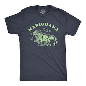 May include: A dark navy blue short-sleeve t-shirt featuring a light green graphic of an iguana with the text MARIGUANA arched above it. The design includes small cloud-like shapes near the iguana, and the shirt has a crew neckline.
