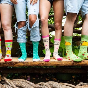 May include: Five pairs of colorful socks with humorous sayings and images. The socks feature a taco, a heart, a chicken, and a green design.