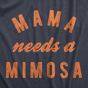Puede incluir: Una camiseta azul marino con el texto "MAMA needs a MIMOSA" impreso en naranja.