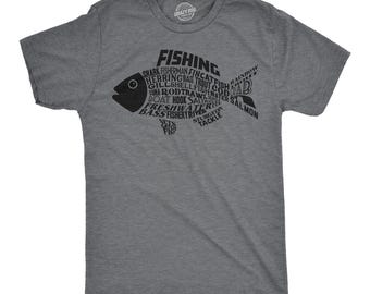 May include: A heather grey short-sleeve t-shirt featuring a large black graphic of a fish. The fish shape is composed of various fishing-related words including Fishing, Shark, Fisherman, Trout, Cod, Salmon, Bass, and others, with a solid black head.