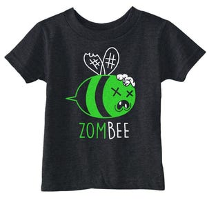 Puede incluir: Una camiseta de manga corta gris carbón con un gráfico de una abeja zombi verde con rayas negras, ojos en forma de X y alas blancas. El texto ZOMBEE está impreso debajo del gráfico en letras verdes y blancas en la parte frontal de la prenda.