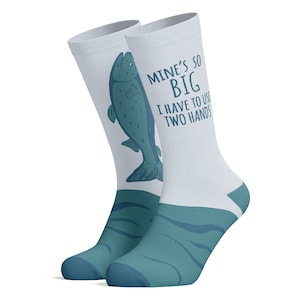 May include: A pair of white socks with a blue fish graphic and the text "Mine's so big I have to use two hands". The socks have a blue and white wave pattern at the bottom.
