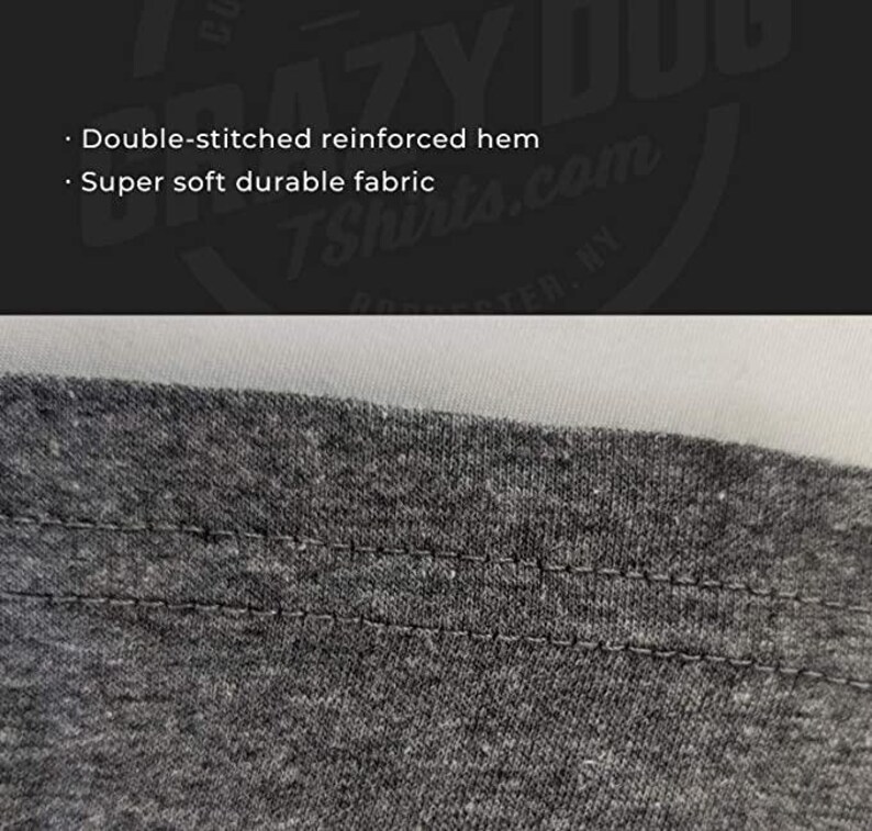 May include: Close-up of a gray t-shirt hem with a double-stitched reinforced hem. The stitching is visible and the fabric appears soft and durable.