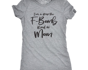 May include: A heather gray short-sleeved t-shirt featuring black text printed on the front that reads, I'm a drop the F-Bomb Kind of Mom. The shirt has a crew neckline and a standard fit, with a small circular logo printed inside the neck area.