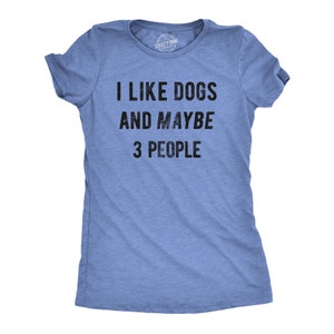 May include: A light blue t-shirt with the text "I LIKE DOGS AND MAYBE 3 PEOPLE" in black. The shirt is made of a soft material and has short sleeves. The Crazy Dog brand logo is visible on the neckline.