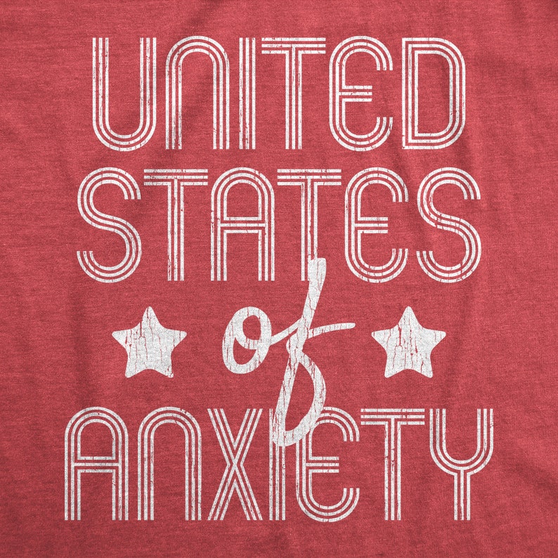 May include: Red t-shirt with the distressed text "UNITED STATES of ANXIETY" in white, with two white star graphics. The text is in a bold, vintage-inspired font.