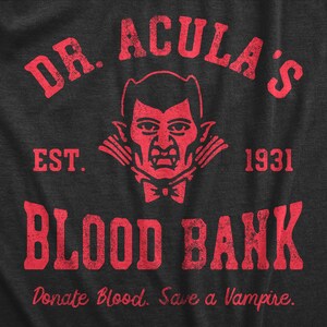 Puede incluir: Impresi&oacute;n gr&aacute;fica roja en una camiseta gris oscuro que dice "DR. ACULA'S EST. 1931 BLOOD BANK Donate Blood. Save a Vampire."
