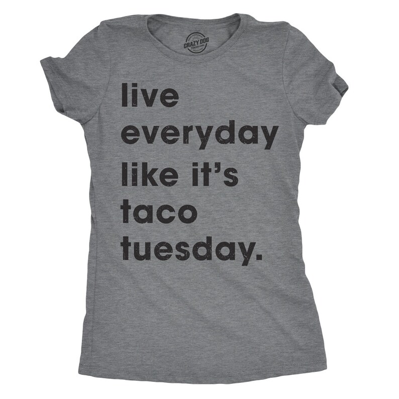 May include: A grey t-shirt with the slogan "Live everyday like it's taco tuesday." The text is in black, and the shirt has short sleeves and a crew neck. The brand name "Crazy Dog" is printed at the top.