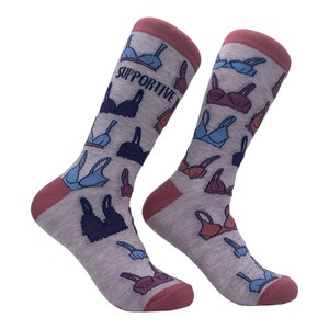 May include: A pair of grey socks with a pink trim. The socks feature a pattern of colorful bras with the word "Supportive" printed on one sock.