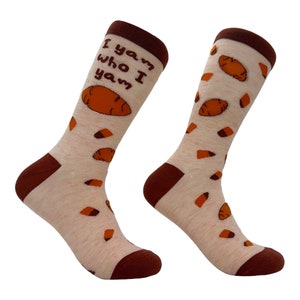 May include: A pair of cream-colored socks with a brown cuff and brown yam illustrations. The socks have the text "I yam who I yam" printed on one sock.