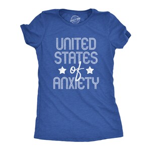 May include: A blue t-shirt with the text "UNITED STATES of ANXIETY" in white, with two star graphics. The shirt is a crew neck style.