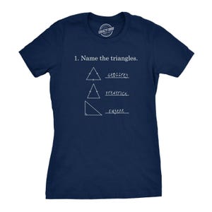 May include: A navy blue short-sleeve t-shirt featuring white text that reads 1. Name the triangles. Below the text are three white line-drawn triangles with lines for answers labeled Geoffrey, Frederick, and Eugene in a handwritten font style.