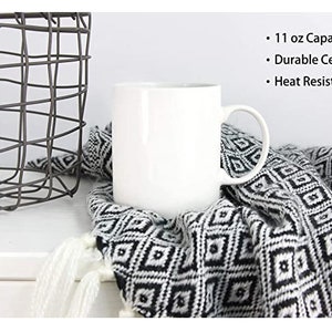 May include: White ceramic mug with a 11 ounce capacity. The mug is heat resistant and has a handle. The mug is sitting on a black and white patterned blanket.