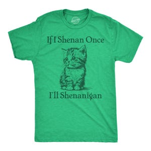 Op de afbeelding: Een groen t-shirt met de tekst "If I Shenan Once I'll Shenanigan" en een gedetailleerde illustratie van een katje. Het shirt is effen groen van kleur en heeft een ronde hals.