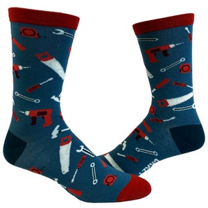 May include: A pair of blue socks with a red cuff. The socks feature a pattern of various tools, including a saw, a wrench, a hammer, and a drill.