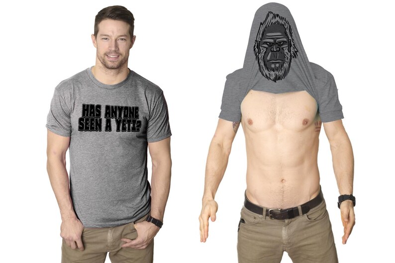 May include: A heather grey t-shirt with the text "Has anyone seen a Yeti?" printed on the front. The t-shirt has a hidden design that reveals a Yeti face when the shirt is pulled up over the head.