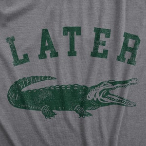 May include: Gray t-shirt with a distressed green graphic of an alligator and the word "LATER" above it. The alligator is detailed with open jaws, and the text has a vintage, worn look.
