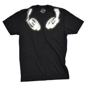 May include: A black short-sleeved t-shirt featuring a white graphic print of over-ear headphones positioned at the neckline. The inner collar label displays the text Crazy Dog. The design is centered on the chest area of the garment.
