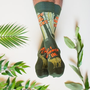 May include: A pair of green socks with a deer and forest print. The socks have the text "I like big bucks and I cannot lie" printed on them.