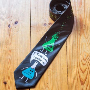 May include: A black tie with a green and blue beaker graphic and the text "I think you're overreacting".