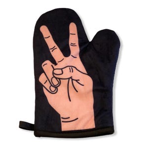 May include: A black oven glove featuring a large, light-toned graphic of a hand making a peace sign gesture. The hand illustration is outlined in dark lines, showing the index and middle fingers extended upward while the thumb and other fingers are folded.
