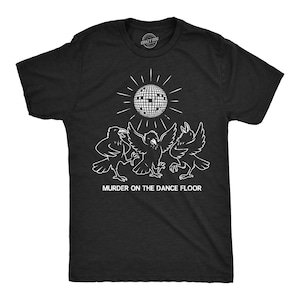May include: Black t-shirt with a white graphic featuring three crows dancing under a disco ball. The text "MURDER ON THE DANCE FLOOR" is printed below the graphic. The shirt has a crew neck and short sleeves.