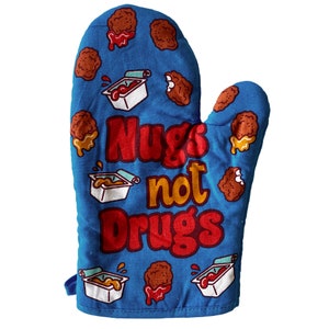 Op de afbeelding: Blauwe ovenwant met een rood, geel en wit ontwerp. Het heeft de tekst "Nugs not Drugs" en afbeeldingen van kippenvleeskroketten en dipsaus.