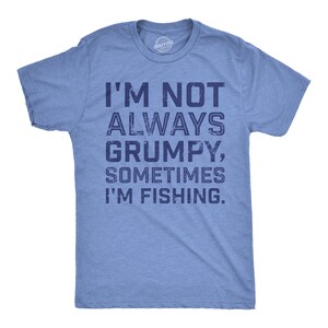 Peut inclure: Un t-shirt bleu chiné à manches courtes avec un col rond. L'avant présente un texte bleu foncé à l'aspect vieilli qui indique : I'M NOT ALWAYS GRUMPY, SOMETIMES I'M FISHING. Le t-shirt a une coupe standard avec un ourlet droit.