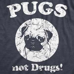 May include: A distressed white graphic on a navy blue t-shirt with a pug dog and the text "PUGS not Drugs!"