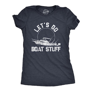 May include: A dark heather navy blue short-sleeve t-shirt featuring a white distressed graphic of a motorboat and a circular sun outline. The text "LET'S DO BOAT STUFF" is printed in a bold, weathered white font above and below the boat illustration.