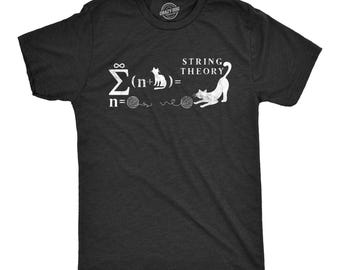Puede incluir: Una camiseta gris carbón de manga corta con un estampado gráfico blanco de una ecuación matemática con gatos y ovillos de lana, que incluye el texto "STRING THEORY" y un símbolo de sumatoria con un gato y un ovillo.