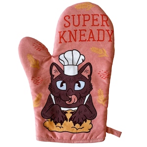 May include: A pink oven mitt with a black cat wearing a chef's hat and kneading dough. The text "SUPER KNEADY" is printed on the mitt.