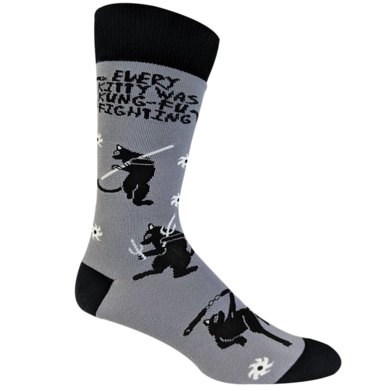 May include: Gray socks with a black and white design of cats fighting with weapons. The text on the socks reads "Every kitty was kung-fu fighting."