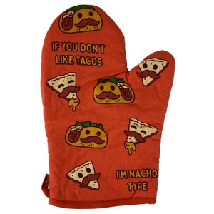 May include: Red oven mitt with a pattern of tacos and tortilla chips with faces. The text "If you don't like tacos I'm Nacho Type" is printed on the mitt.