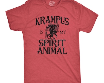 May include: A heather red short-sleeve t-shirt featuring a black graphic of the mythical creature Krampus. The text printed in black reads KRAMPUS IS MY SPIRIT ANIMAL, with the creature illustration positioned between the words KRAMPUS and IS.