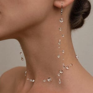 May include: A unique, clear, water droplet-themed jewelry set. The set includes a pair of dangling earrings and a necklace, both featuring multiple clear, round, and teardrop-shaped droplets. The jewelry is designed to appear as if the droplets are floating.