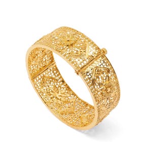 Könnte beinhalten: Ein breiter goldfarbener Armreif mit einem komplizierten Filigranmuster und sich wiederholenden Blumenmotiven. Die Metallarbeit besteht aus zarten, miteinander verbundenen durchbrochenen Designs, die ein durchgehendes Band mit einem Scharnierverschluss bilden.