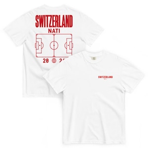 Könnte beinhalten: Ein weißes T-Shirt mit kurzen Ärmeln und roten Grafiken. Auf der Vorderseite steht der Text SWITZERLAND NATI. Die Rückseite zeigt ein großes rotes Fußballfeld-Diagramm, den Text SWITZERLAND NATI und den Text 20 Globus 24 in roter Farbe.